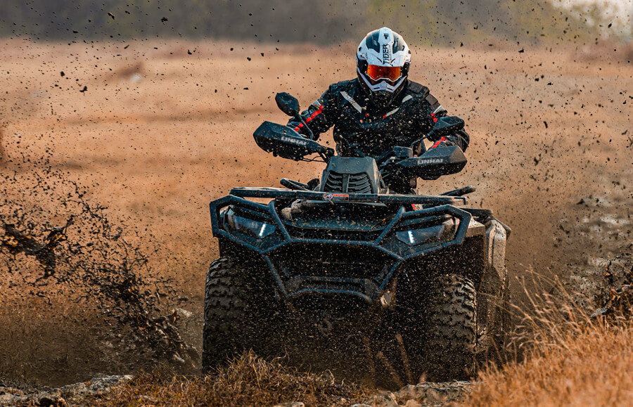 Linhai Landforce 1000L EPS w akcji – jazda po błocie, kierowca w kasku z rozbryzgami błota