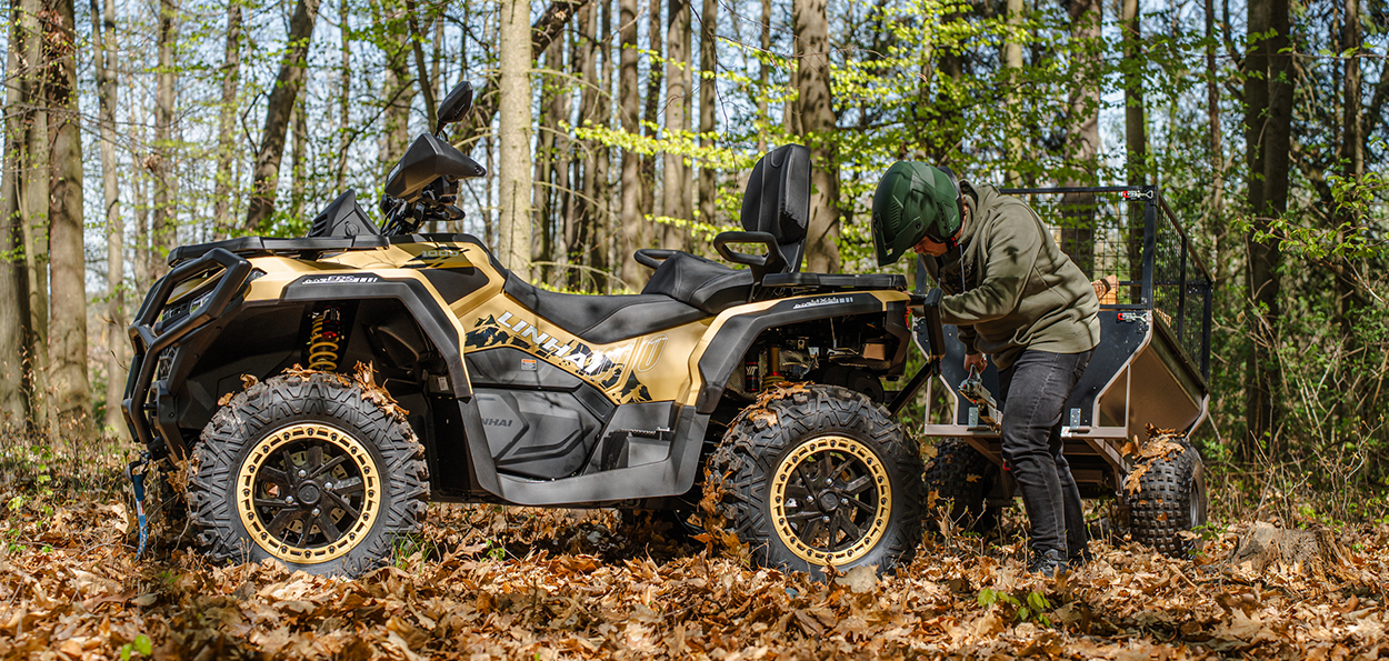 Linhai Landforce 1000L EPS w wersji piaskowej z podpiętą przyczepą roboczą w lesie