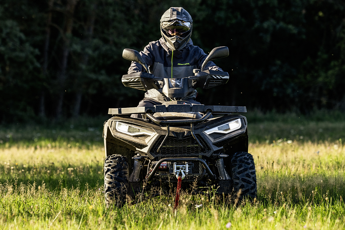 Linhai Promax 420 w akcji – kierowca w pełnym kasku na łące, ujęcie z przodu o zachodzie słońca